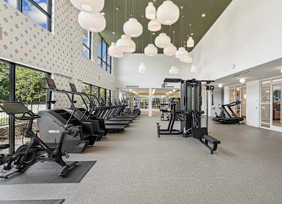 A gym with a row of treadmills and elliptical machines.