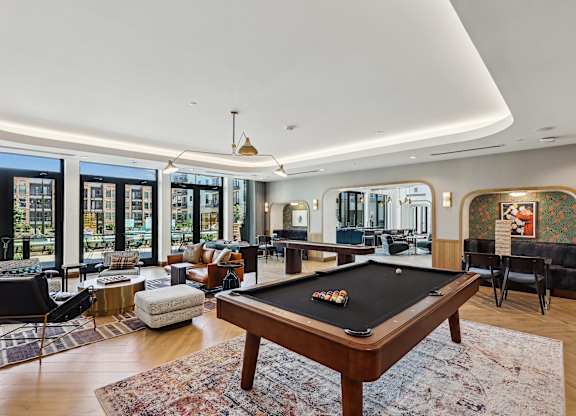 A pool table is in the middle of a room with a view of the city.