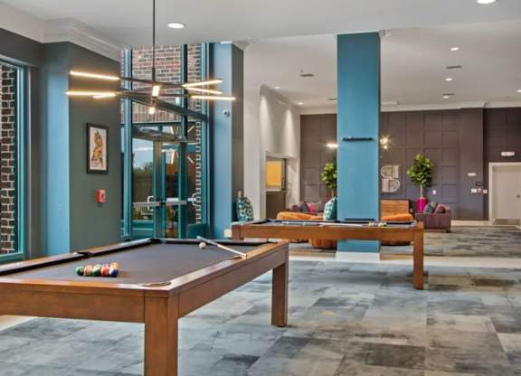 A pool table is in the middle of a room with a blue column and a couch.