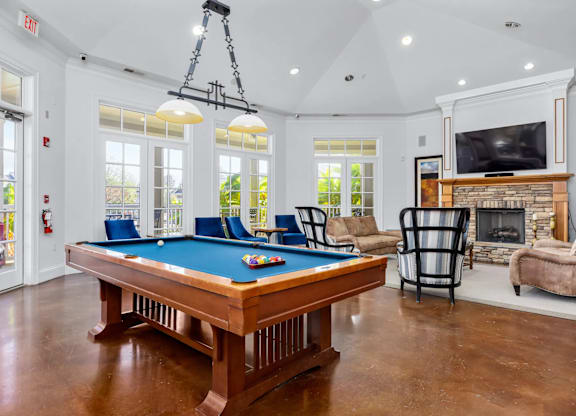 A pool table is in the middle of a room with a fireplace and a television.