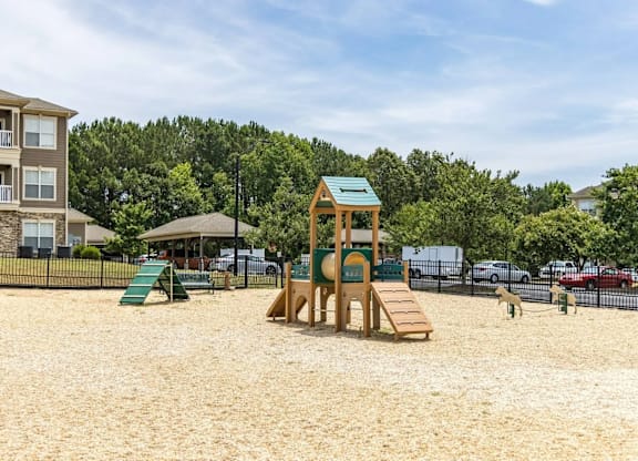 A playground with a wooden structure and a green slide.