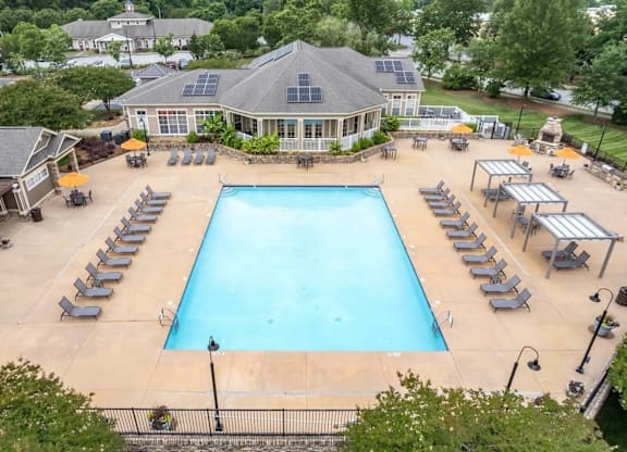 A large swimming pool surrounded by sun loungers and umbrellas.