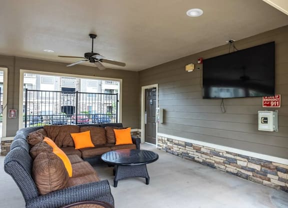 A living room with a black sofa and a television on the wall.