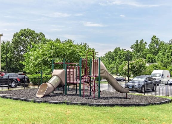 A playground with a slide and a green lawn.