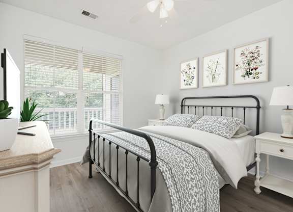 A bedroom with a black metal bed frame and a white bedspread.