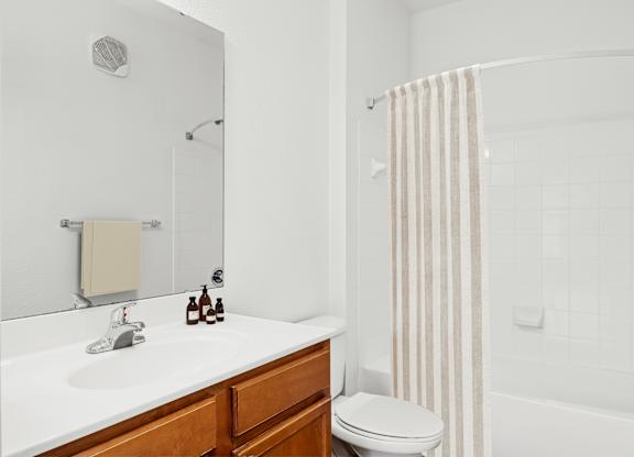 A white bathroom with a toilet, sink, and shower.