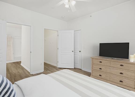 A bedroom with a bed, dresser, and television.