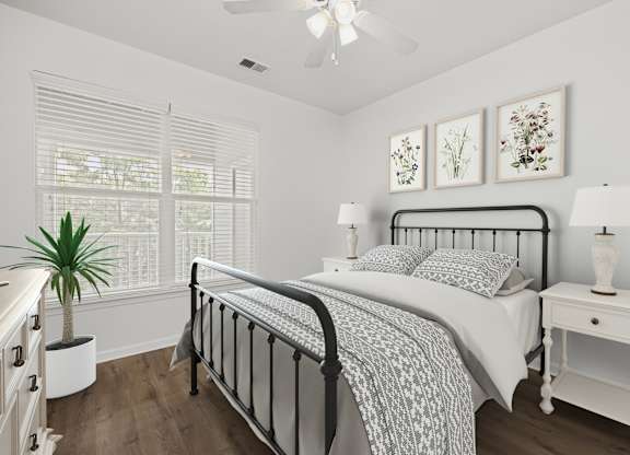 A bedroom with a bed, nightstand, and a plant.