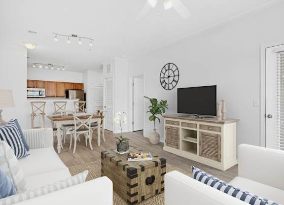 A living room with a white couch, a wooden entertainment center, and a dining table.