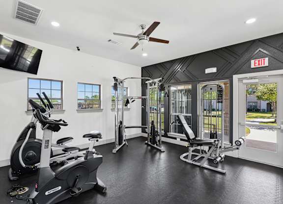 A gym with a variety of equipment including a stationary bike, a rowing machine, and a treadmill.