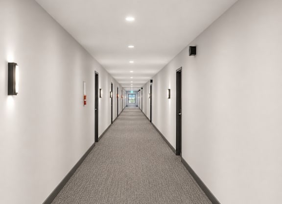 A long hallway with carpeted floors and white walls.