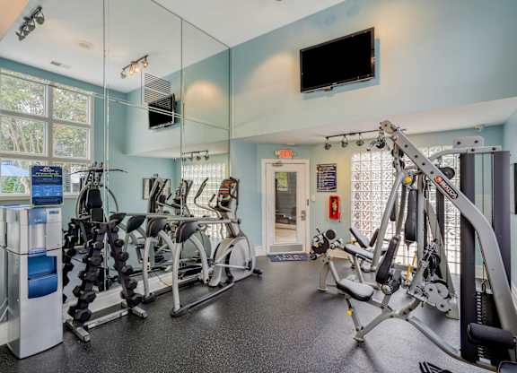 A gym with a row of exercise bikes and a television mounted on the wall.