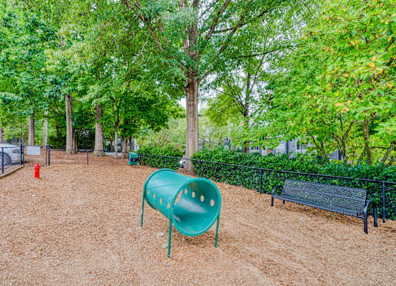A playground with a green slide and a red fire hydrant.