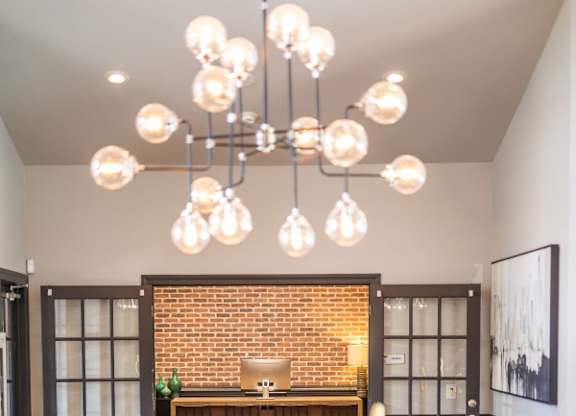 A living room with a brown couch and a chandelier.