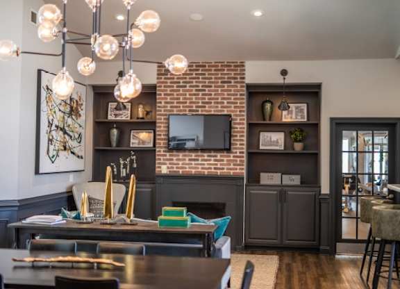 A dining room with a brick wall and a television above it.