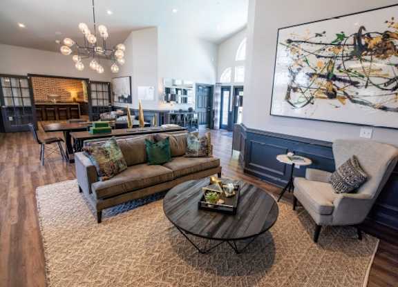 A living room with a brown sofa, a grey armchair, and a coffee table with a painting on the wall.