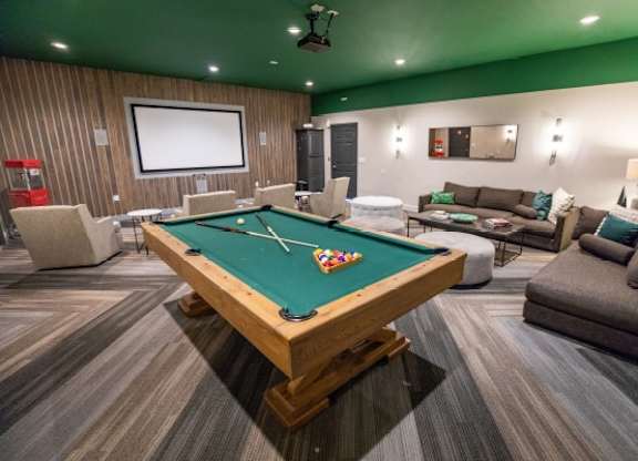 A pool table is in the middle of a room with a couch and a television.