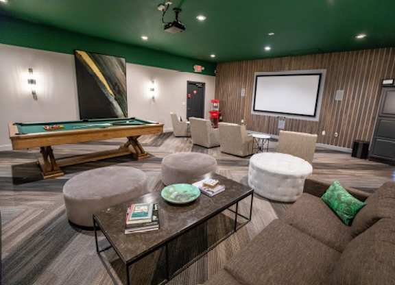 A room with a pool table, a couch, and a television.