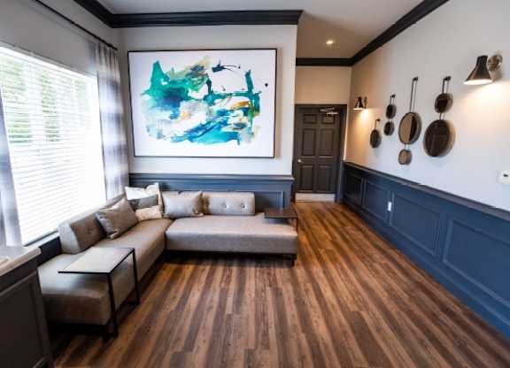 A modern living room with a large abstract painting on the wall.