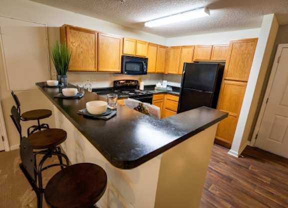 A kitchen with a black counter top and wooden cabinets.