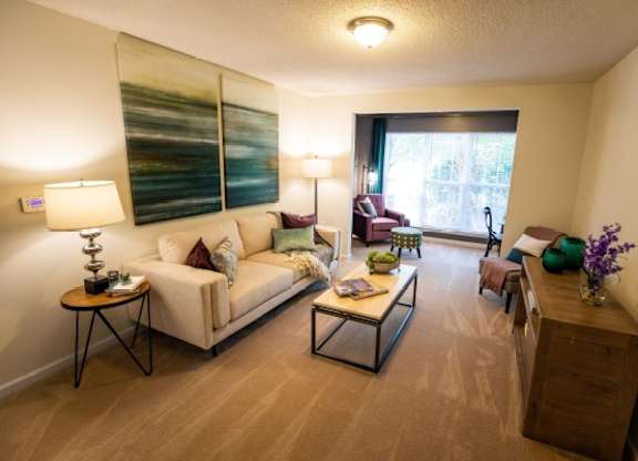 A living room with a white couch, a coffee table, and a side table with a lamp.