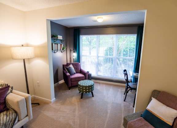 A living room with a couch, chair, ottoman, and lamp.