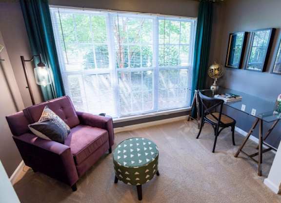 A living room with a purple chair and ottoman.