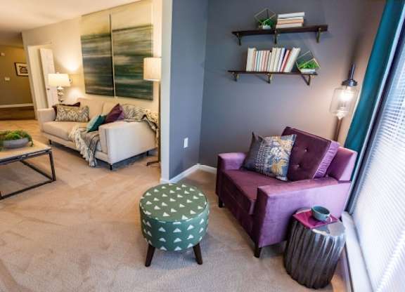A living room with a purple couch and a green ottoman.