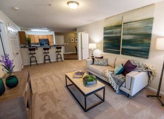A living room with a couch, coffee table, and a painting on the wall.