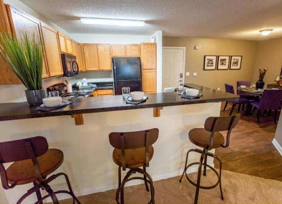 A kitchen with a bar area and chairs.