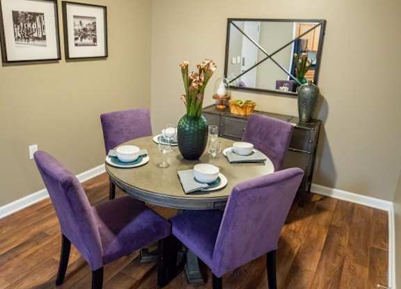 A dining room with a table set for two and purple chairs.