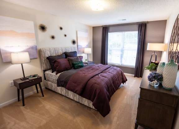 A bedroom with a large bed and a round mirror on the wall.