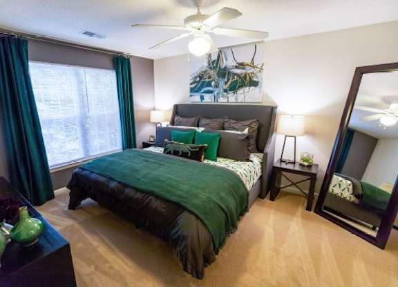 A bedroom with a bed, nightstand, and a mirror.