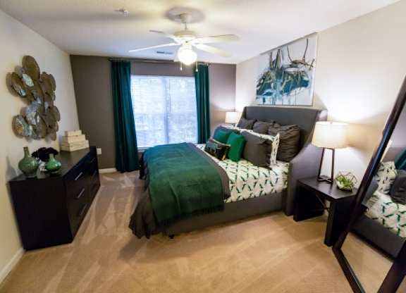 A bedroom with a bed, nightstand, and a ceiling fan.