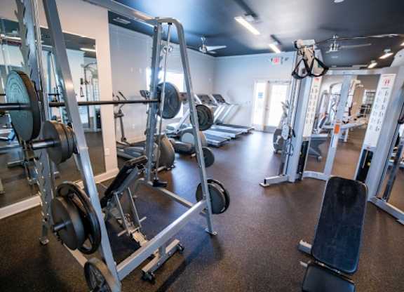 A gym with a variety of equipment including weight machines and a bench press.