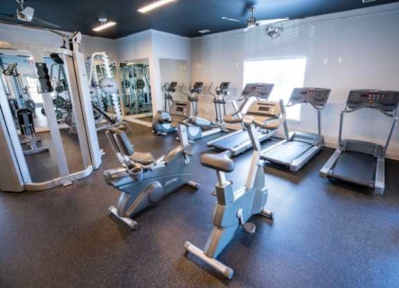 A gym with a variety of equipment including treadmills, stationary bikes, and weight machines.