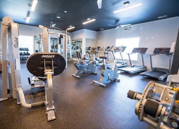 A gym with a variety of equipment including a weight bench and a leg press machine.