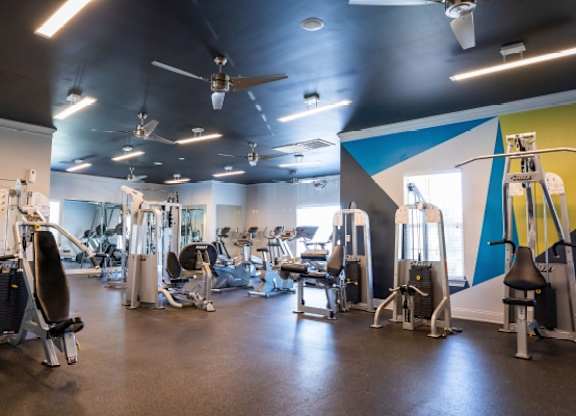 A gym with a variety of equipment including treadmills, weights, and exercise machines.