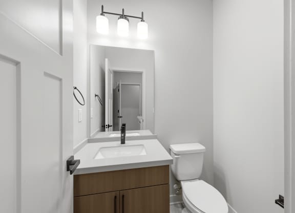 A bathroom with a toilet, sink, and mirror.