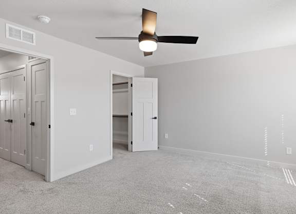 A room with a ceiling fan and a doorway leading to another room.
