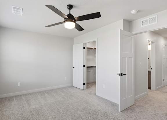 A room with a ceiling fan and carpeted floor.