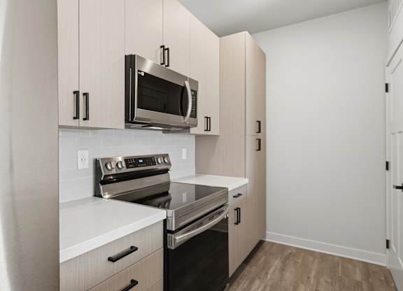 A kitchen with a stainless steel refrigerator, a microwave above the stove, and white cabinets.