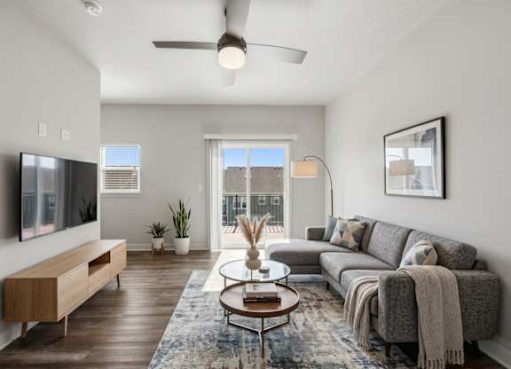 A modern living room with a grey sofa, a wooden cabinet, a coffee table, and a flat-screen TV.