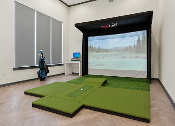 A room with a golf simulator and a golf bag.