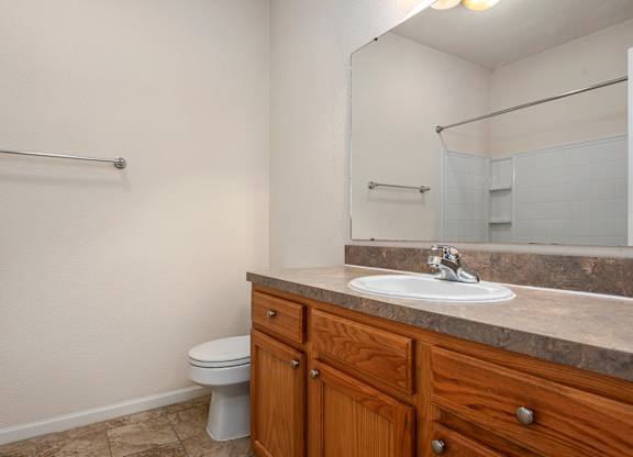 A bathroom with a toilet, sink, and mirror.