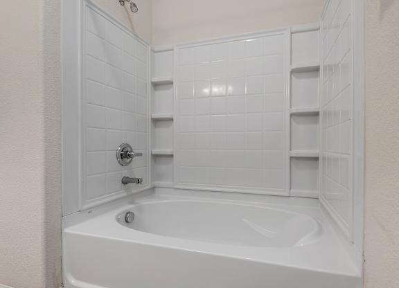A white bathtub with a shower door open.