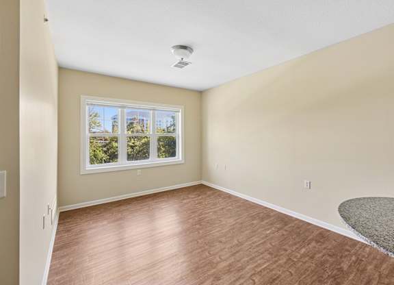 A room with a window and wooden flooring.