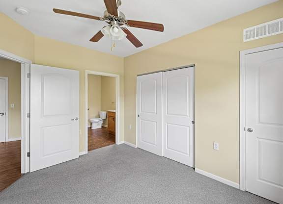 A room with a ceiling fan and white doors.