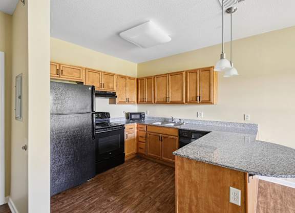 A kitchen with wooden cabinets and a black refrigerator.