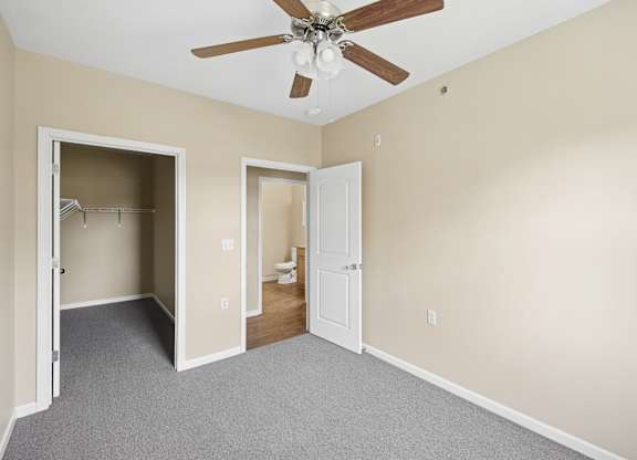 A room with a ceiling fan and two open doors.